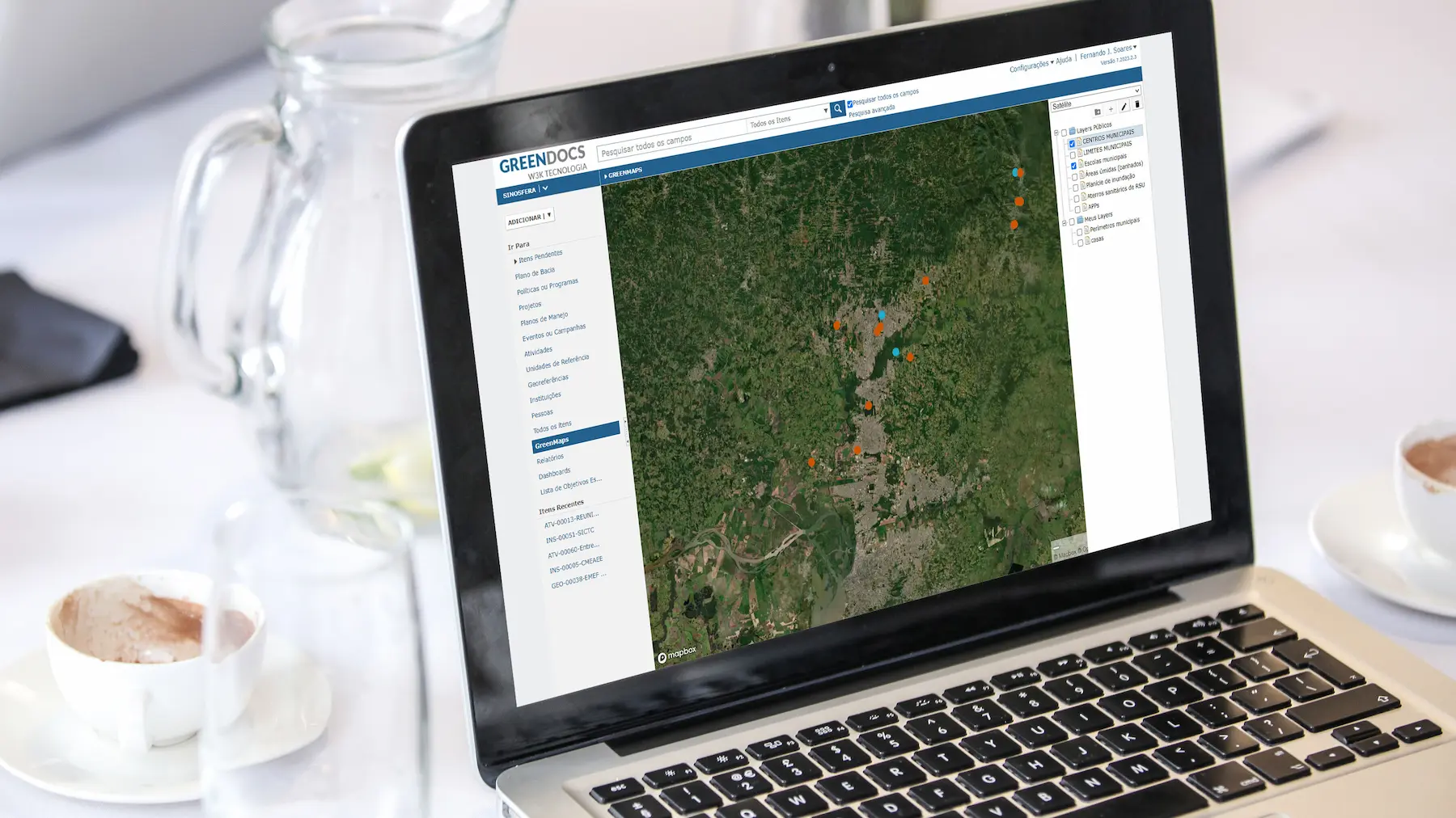 Imagem de um laptop exibindo o sistema Greendocs com um mapa interativo de áreas verdes em detalhes.