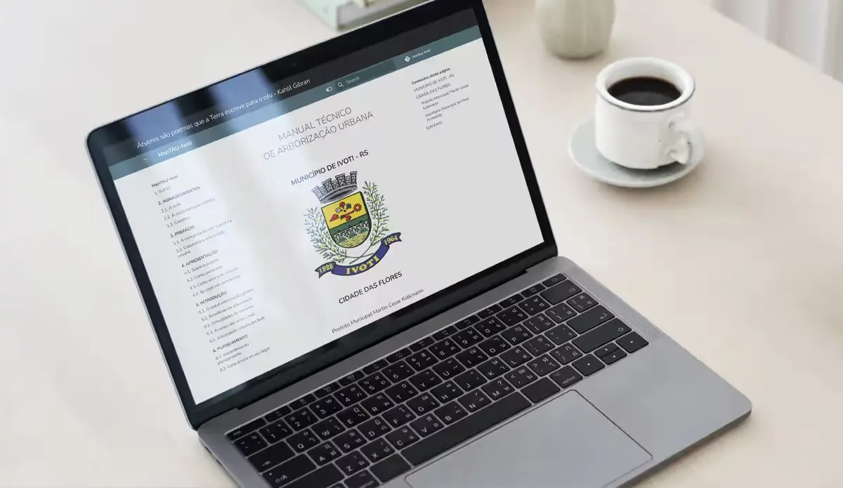 Imagem de um laptop exibindo o site do Manual Técnico de Arborização Urbana do município de Ivoti, RS, com uma xícara de café ao fundo.