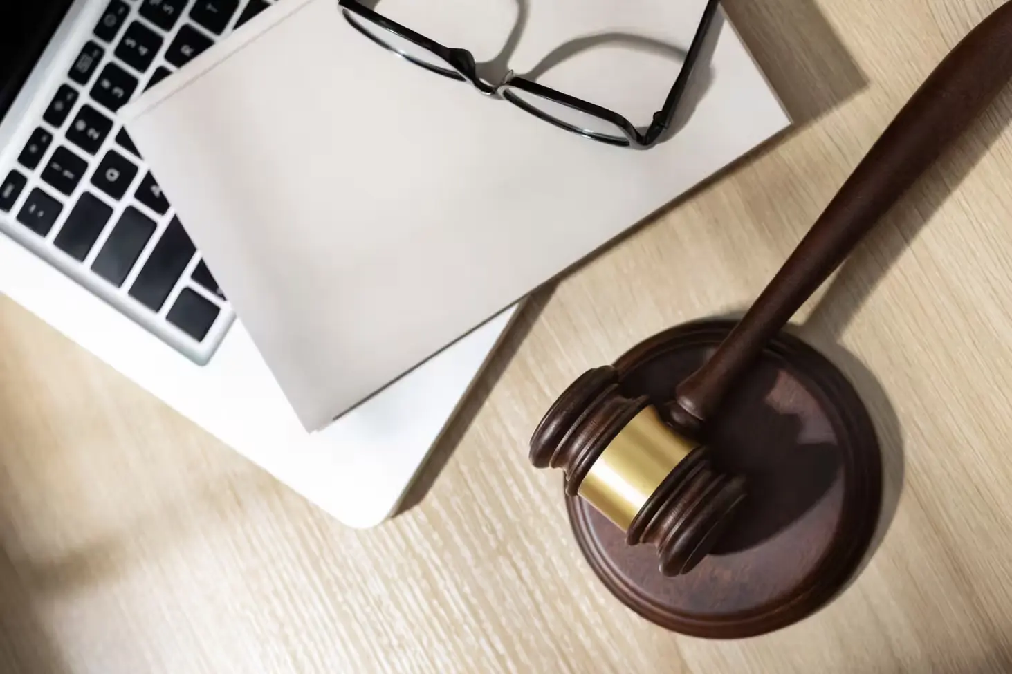Uma mesa de escritório com um laptop, papéis e um martelo de juiz, simbolizando assuntos jurídicos e advocacia.